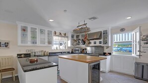 A modern kitchen with white cabinetry, a central island, and a view of the outdoors through a window. - 220W: Lovely Avalon home + walking distance to the beach, restaurants and more. (Avalon)