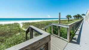 Un paseo marítimo de madera que lleva a una playa, con vista despejada al océano.