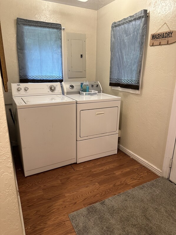 A laundry room with two washing machines, a dryer, and a 'WASH & DRY' sign. - Overlooking Old Town yet In a Secluded Forest Setting (Florence)