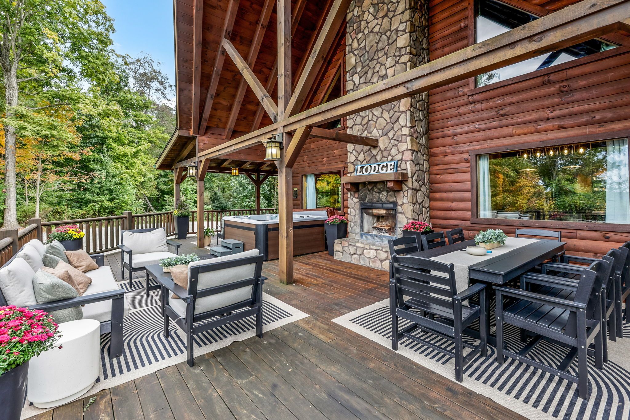 A covered outdoor deck with seating, a stone fireplace, and a sign reading 'LODGUE'.