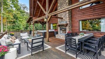 A covered outdoor deck with seating, a stone fireplace, and a sign reading 'LODGUE'.