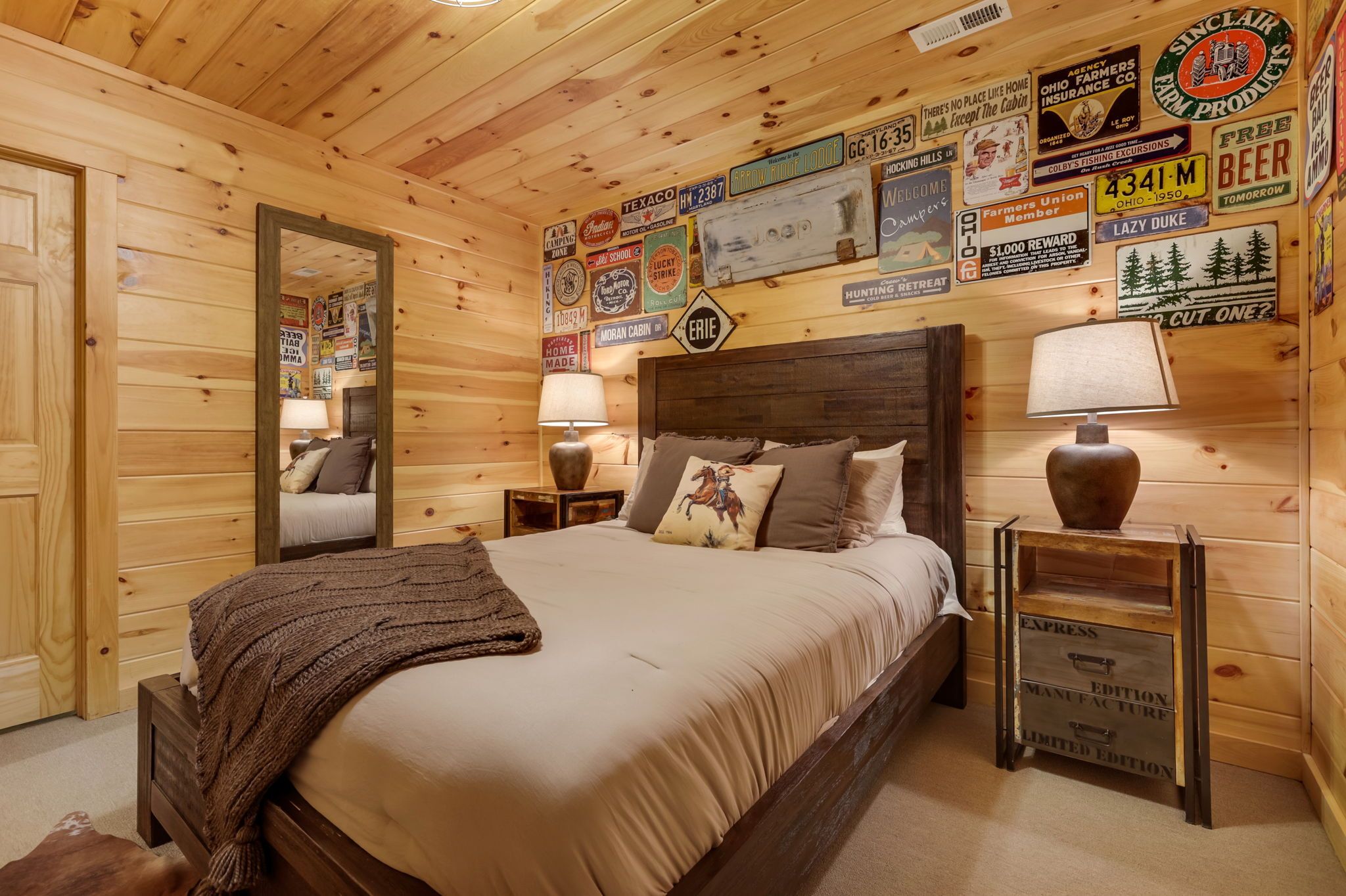 Camera da letto in una baita di legno, con un letto, due comodini, uno specchio e diversi cartelli d'epoca appesi alle pareti.
