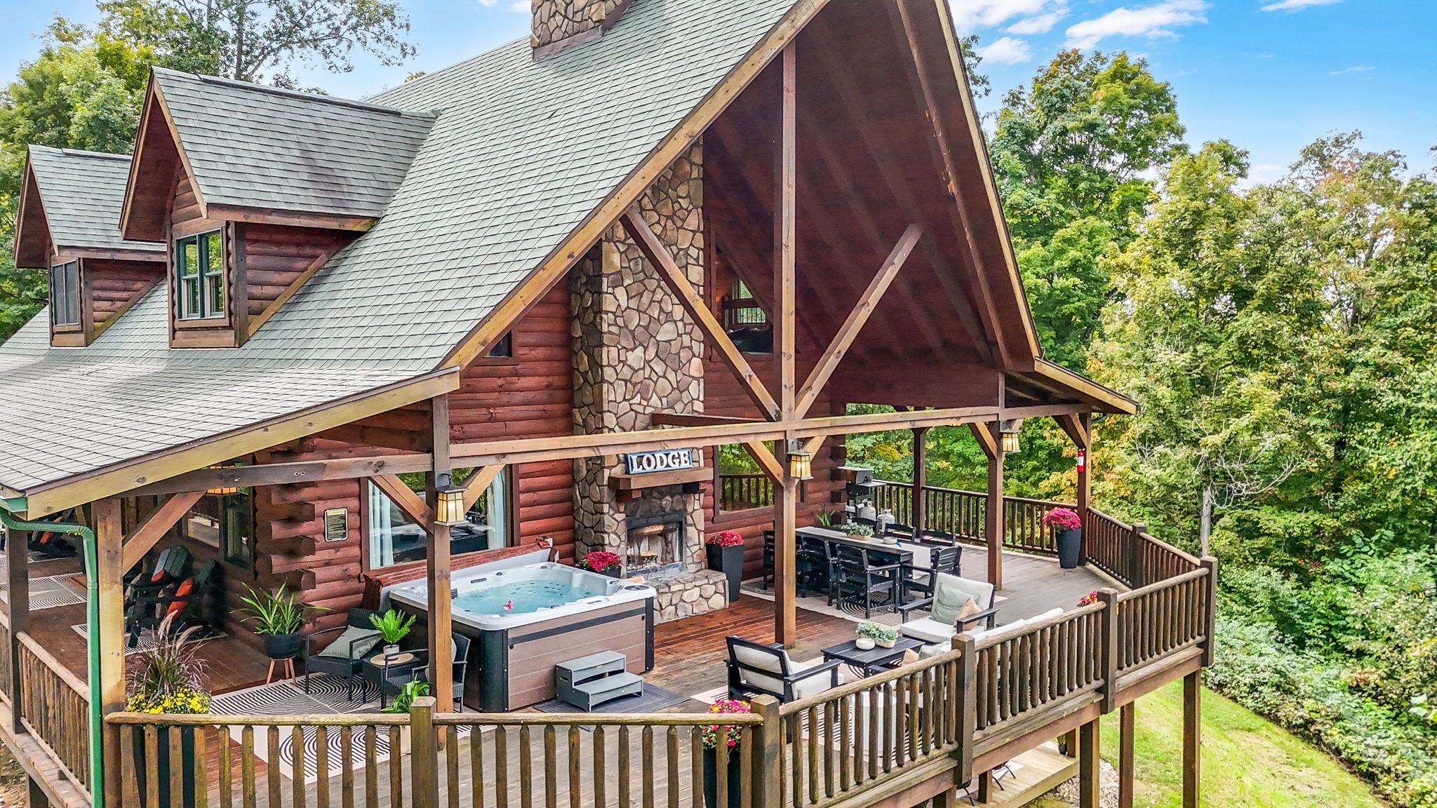 Uma cabana de troncos com hidromassagem, área de estar externa e um deck.