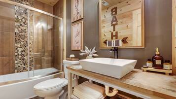 Un bagno con vasca, WC e un mobile lavabo con lavandino e articoli da toilette.