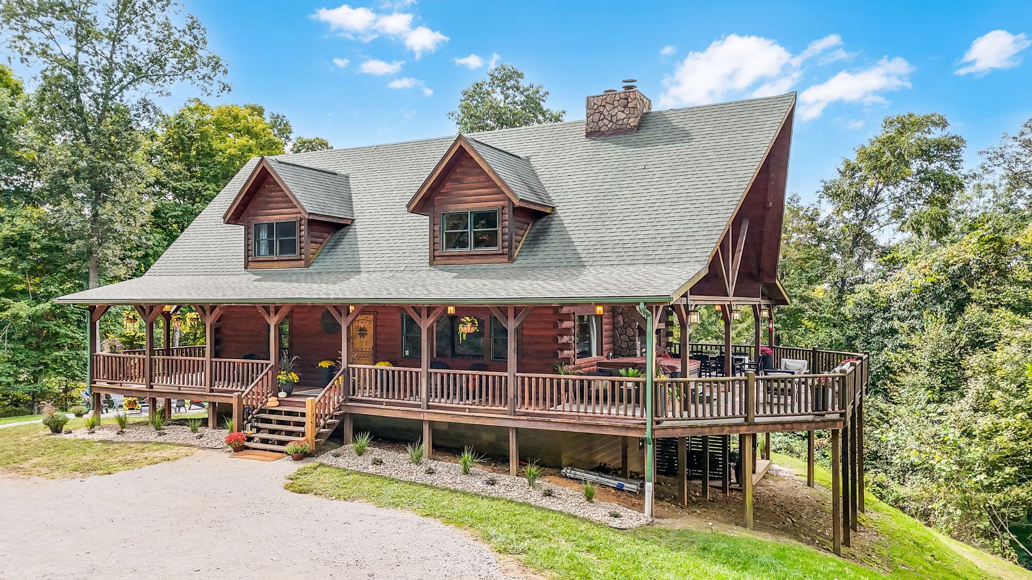 A log cabin with a porch, a chimney, and a deck.