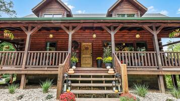 Una baita di legno con un portico, una porta d'ingresso e una scala che vi conduce.