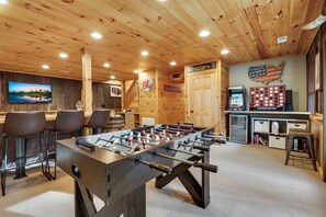 Un espacio interior acogedor con mesa de fútbol, barra y pantalla de televisión.