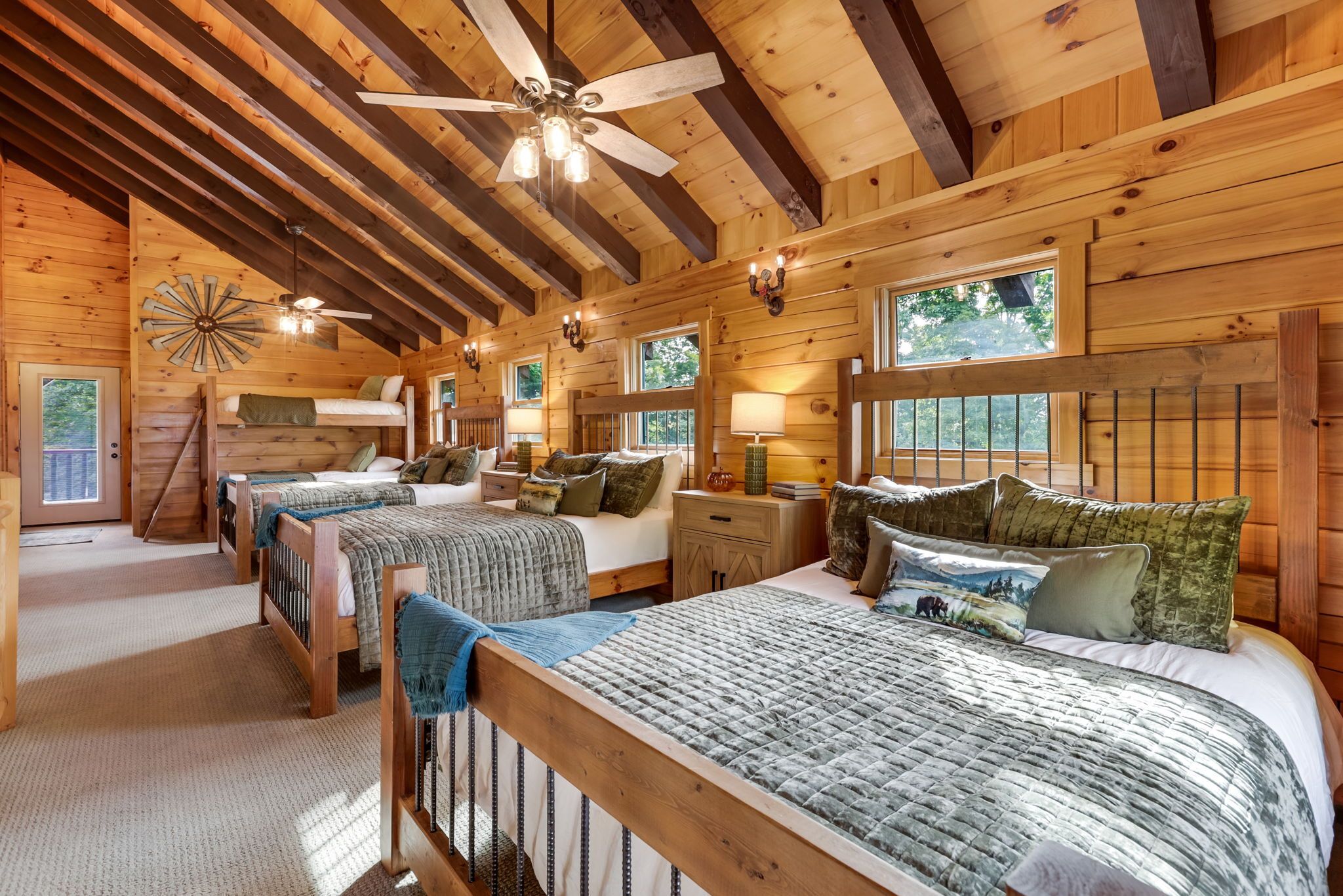 A cabin-style bedroom with two beds, a ceiling fan, and a large window.