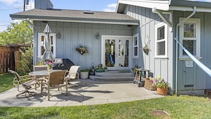 A house with a patio area featuring outdoor furniture and a grill.