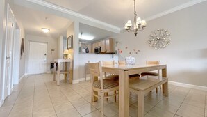 Zona pranzo con tavolo e sedie in legno, un lampadario e un elemento decorativo a parete.