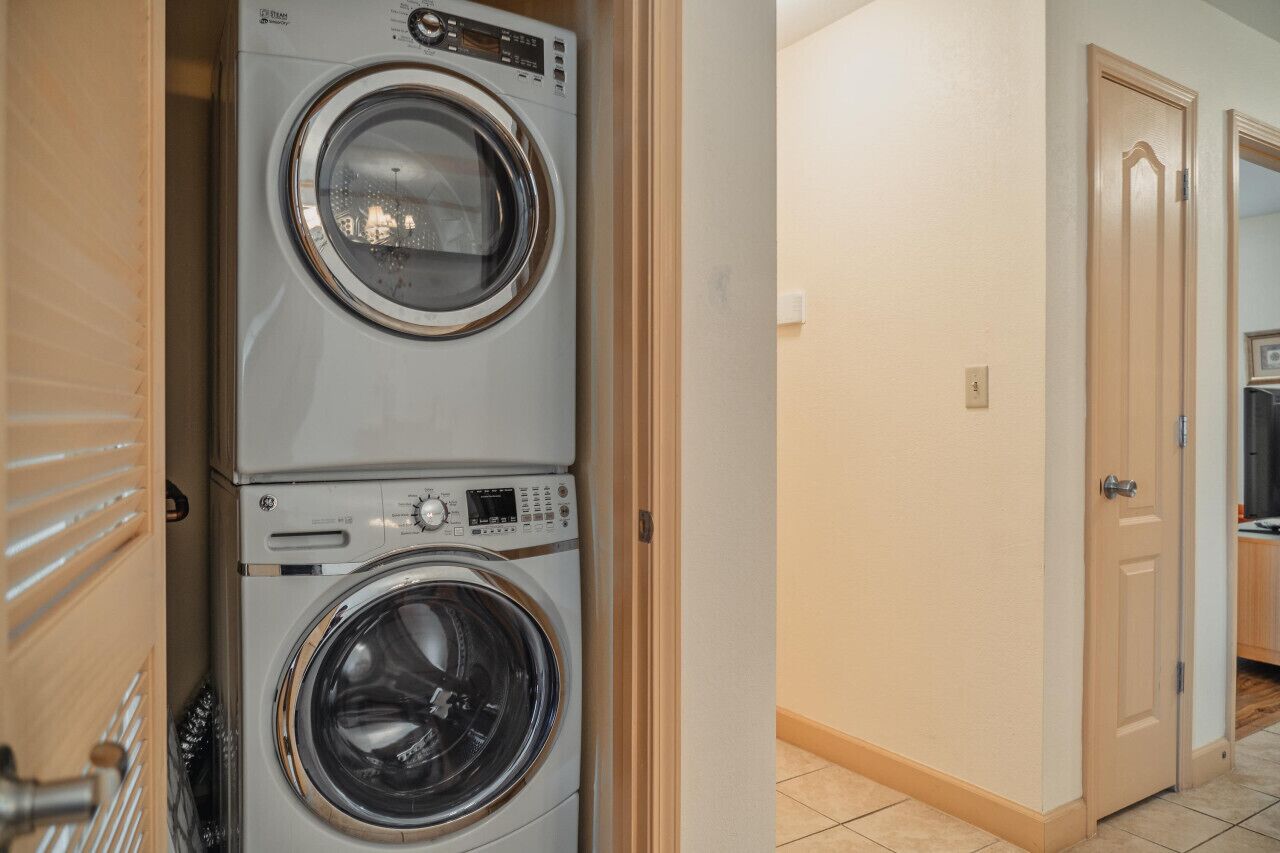 A laundry room with stacked front-loading washers and dryers.