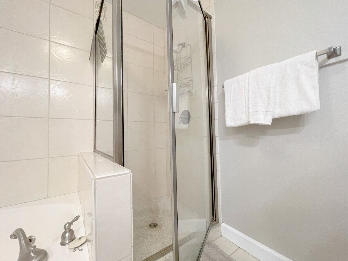 Un baño con ducha de vidrio, una bañera blanca y un perchero para toallas.
