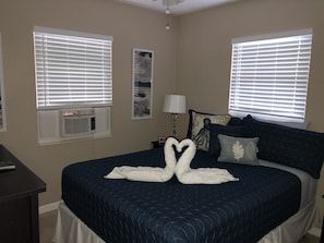 Relax in comfort with a large bed, bedside table, and wall-mounted air conditioning unit.