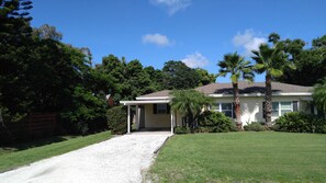 Stunning single-story home with a central entrance, surrounded by lush tropical vegetation and a well-manicured lawn.