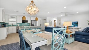 A modern kitchen with white cabinets, a dining table, and a blue sofa in the living area.