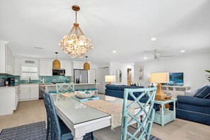 Une cuisine moderne avec des meubles blancs, une table à manger et un canapé bleu dans l’espace salon.