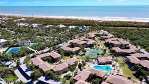 An aerial view of a resort with multiple buildings, a tennis court, and a swimming pool.
