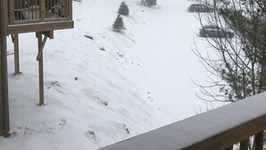 A snowy landscape with a wooden balcony overlooking a snow-covered hill.