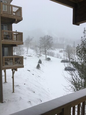 Un paysage enneigé avec un balcon en bois donnant sur une colline recouverte de neige.