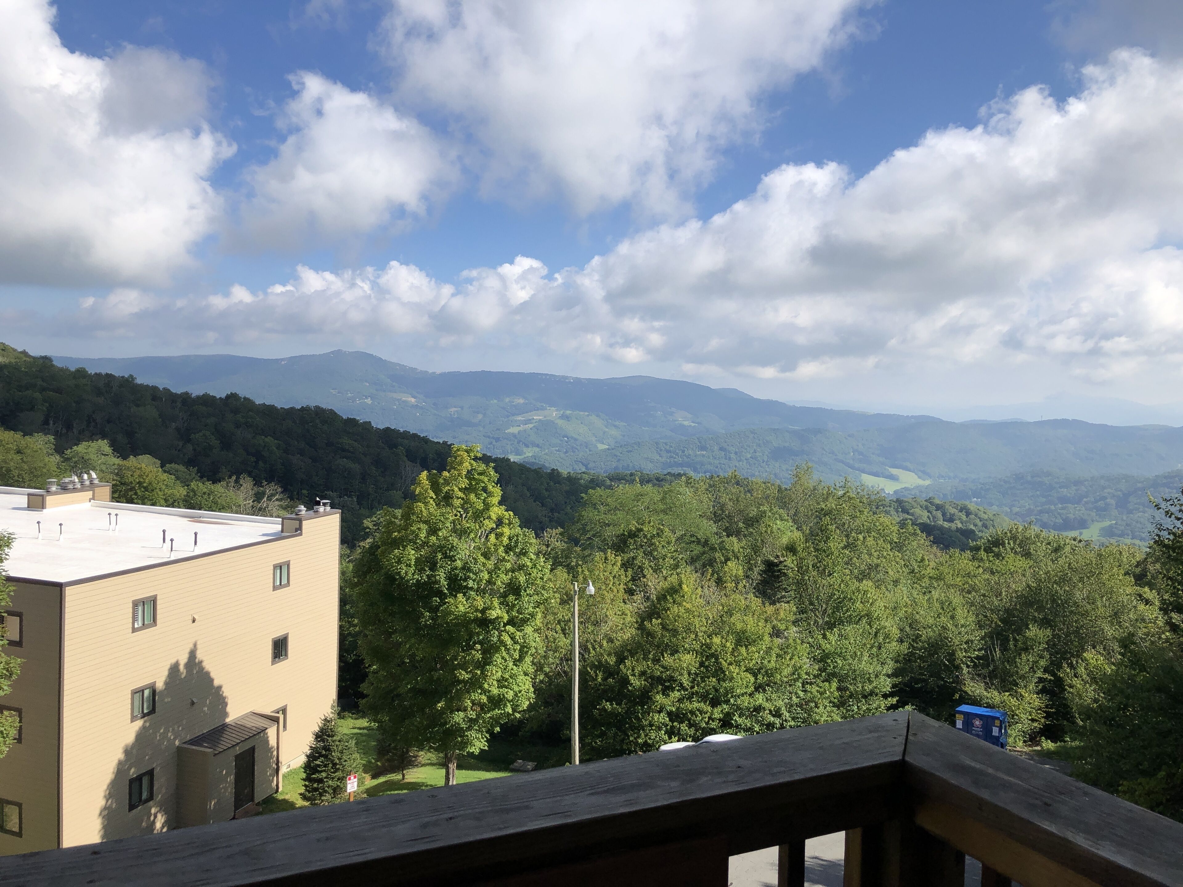 A view from a balcony overlooking a mountainous landscape with a building in the foreground.