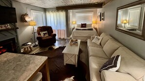 Una sala acogedora con chimenea, un sofá, un sillón y un televisor.