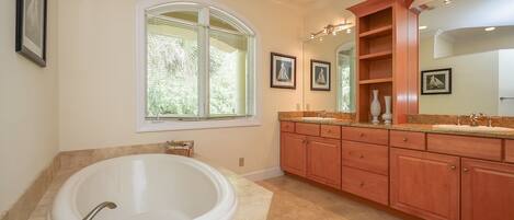 A spacious bathroom with a large bathtub, a vanity with a sink, and a mirror.