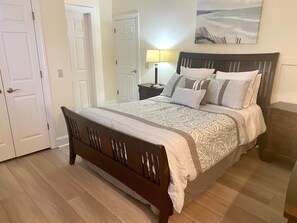 A bedroom with a wooden bed, a nightstand, a lamp, and a painting on the wall.