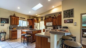 Une cuisine avec des meubles de rangement en bois, un îlot central doté de tabourets, un four à micro-ondes et un réfrigérateur.