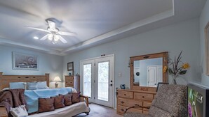 Une chambre à coucher comprenant un lit, une chaise, une commode, un miroir et un ventilateur de plafond.