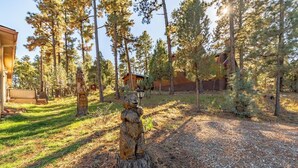 Une zone boisée avec un chalet en bois, une sculpture d’ours et un ciel dégagé.