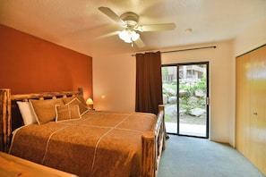 A bedroom with a bed, a ceiling fan, a window with curtains, and a view of an outdoor area.
