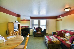 Ein Wohnzimmer mit Kamin, Fernseher, Sofa und Esstisch.