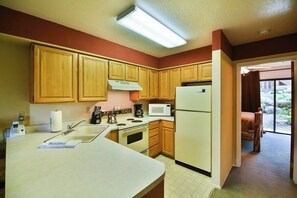 A kitchen with wooden cabinets, a stove, a microwave, and a refrigerator.