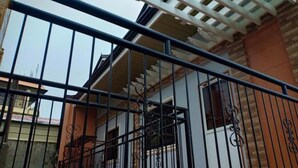 A building with a metal fence, a covered patio area, and brick walls.