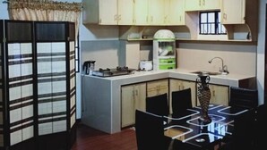 A compact kitchen with a dining area, featuring a refrigerator, a microwave, a sink, and a dining table with chairs.