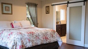 A bedroom with a bed, a dresser, a mirror, and a sliding door leading to another room. -  Country Setting in the Heart of Gold Country - Yet close to it all (Placerville)