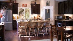 A kitchen with dark wooden cabinets, a stainless steel refrigerator, a dining table with wooden chairs, and a microwave. -  Country Setting in the Heart of Gold Country - Yet close to it all (Placerville)