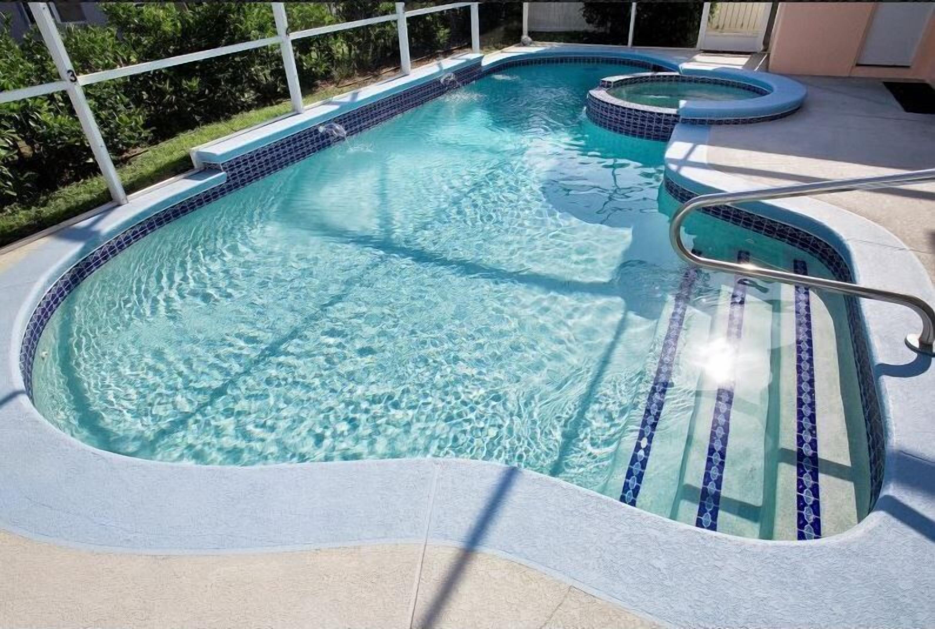 Una piscina con agua azul cristalina, borde de azulejos y una escalera metálica.