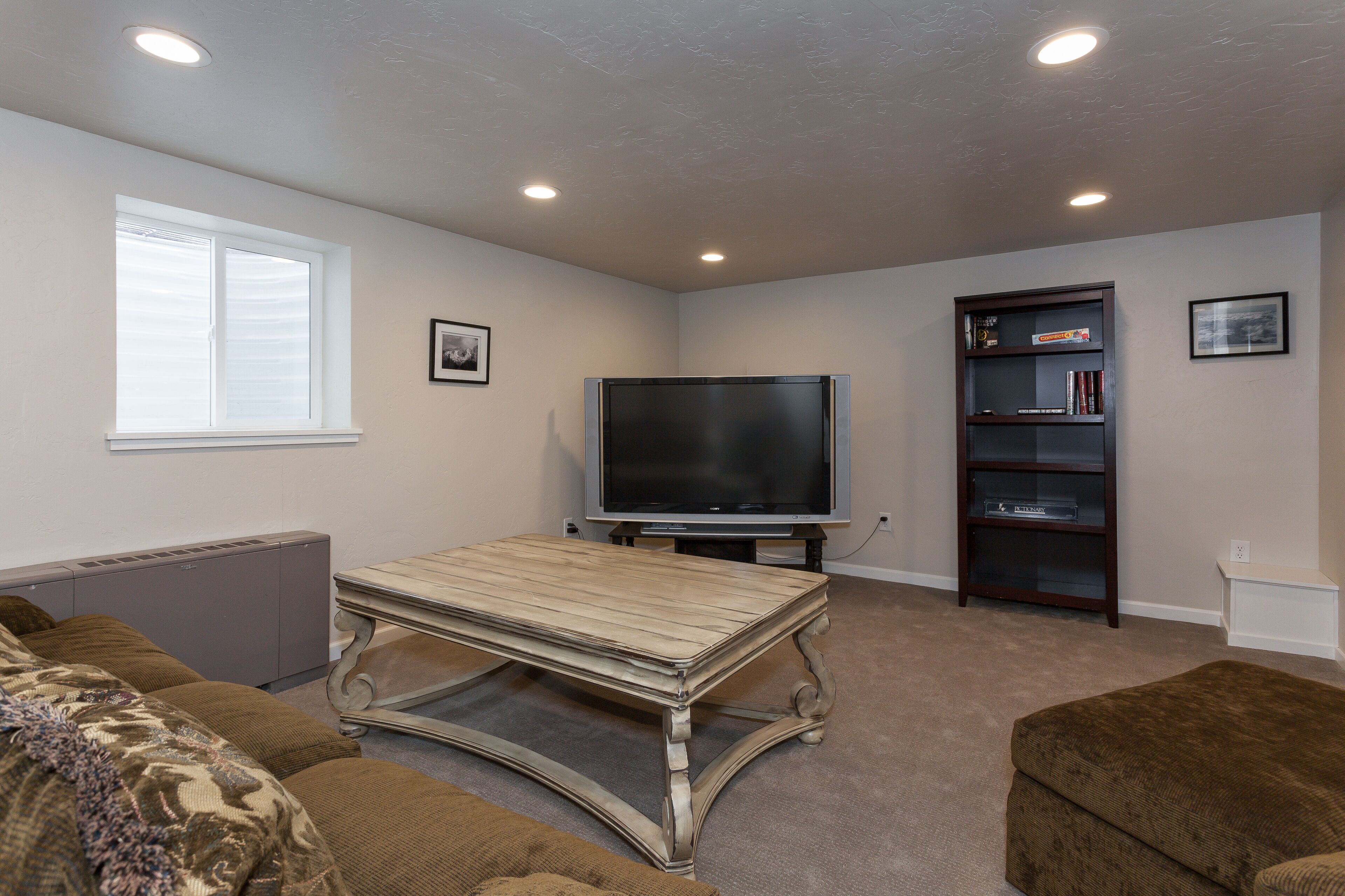 A living room with a TV, bookshelf, and a window.