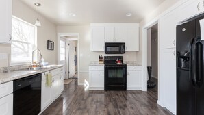 Una cocina moderna con armarios blancos, un refrigerador negro y un microondas.