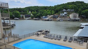 Ein Schwimmbecken mit Liegefläche, Liegestühlen und Blick auf den See und die umliegenden Gebäude.