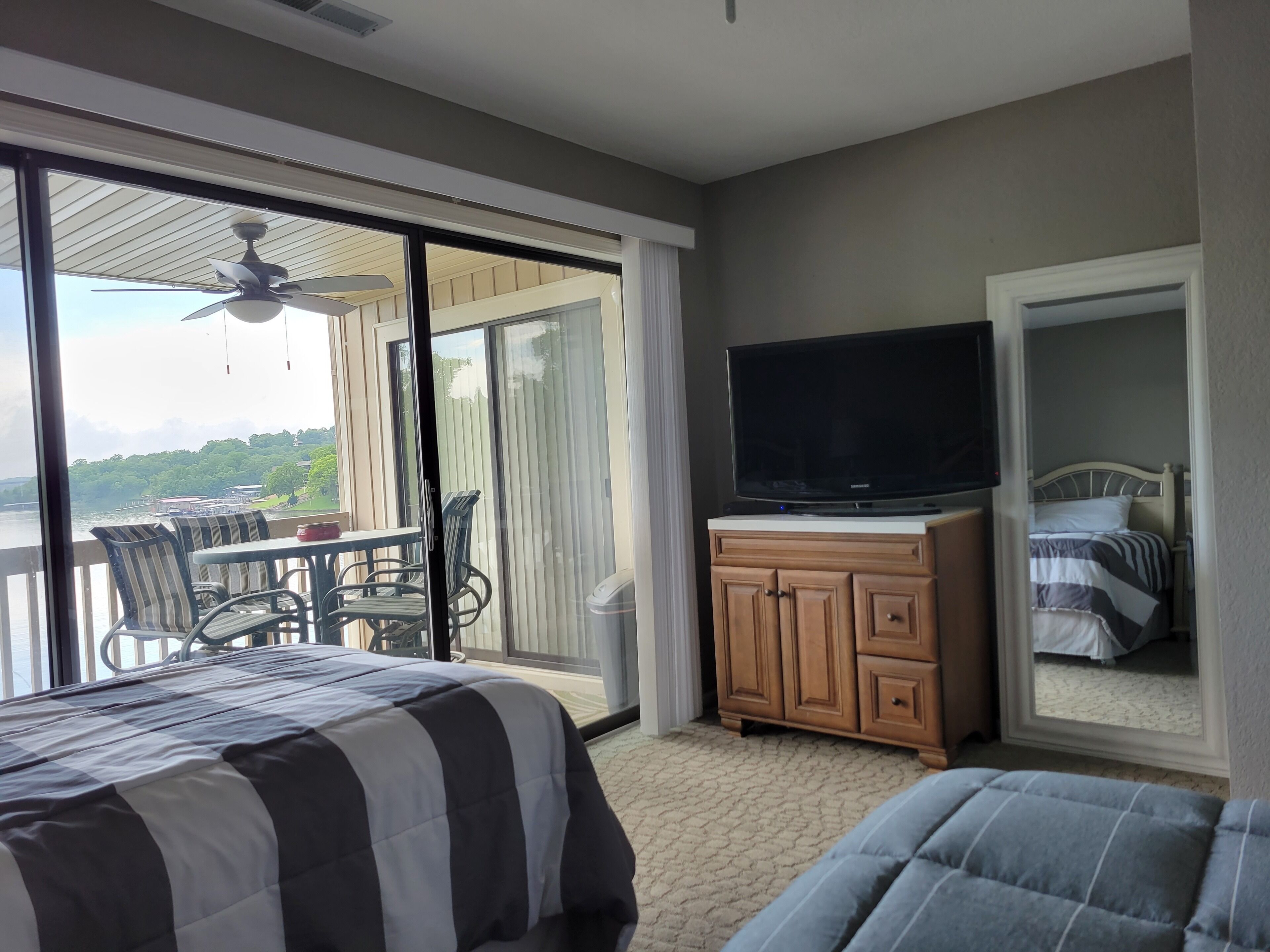 A hotel room with a balcony, a bed, a TV, and a dresser.