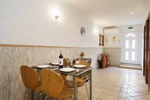 A dining area with a table set for four, chairs, a wine bottle, and glasses.