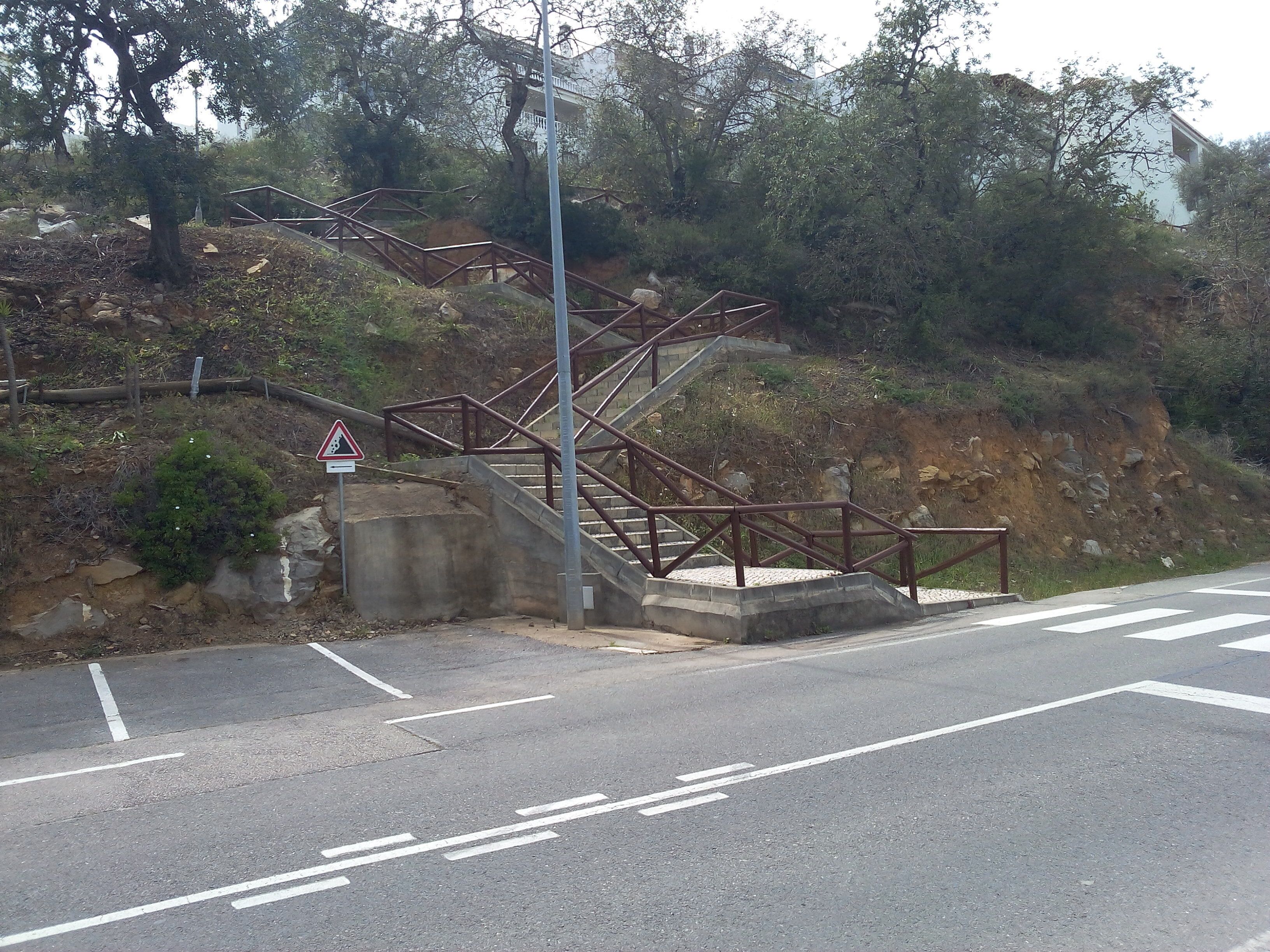 A road with a pedestrian crossing and a staircase leading to a building.