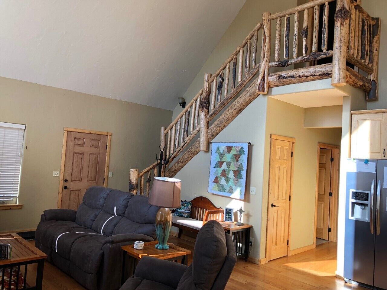 A living room with a sofa, a coffee table, and a lamp. There is a wooden staircase leading to another level.