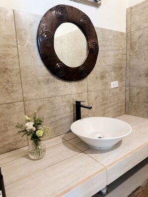 A bathroom with a round mirror, a white sink, and a vase with flowers. - Casa Kennedy - Family Beach Home - Last Private House on West Bay Beach (West Bay)