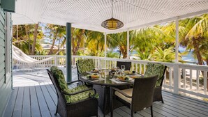 Zona pranzo all'aperto coperta, con mobili in vimini e vista sull'oceano.