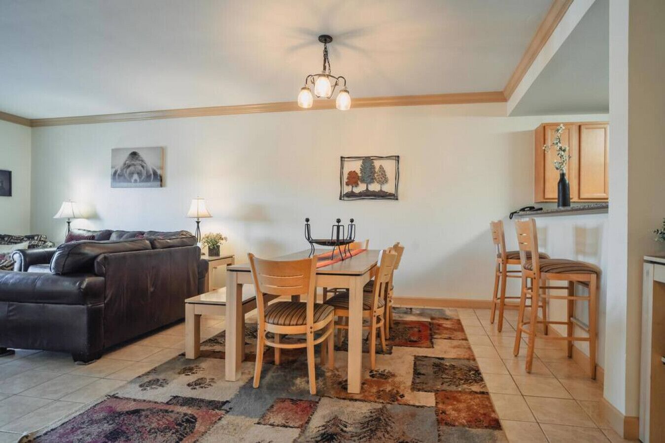 Un salon comprenant un canapé, une table à manger avec des chaises, un tapis et un luminaire au plafond.