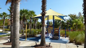 A playground with a yellow canopy, palm trees, and a blue play structure. - Special rates available in Sep and  Oct of 2026 (Kissimmee)