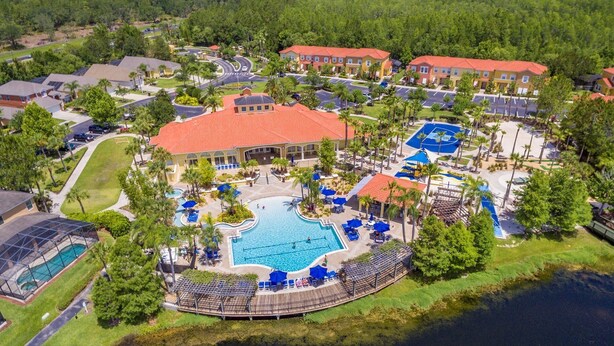 An aerial view of a resort with a central swimming pool, multiple buildings, and a surrounding water body. - Special rates available in Sep and  Oct of 2026 (Kissimmee)